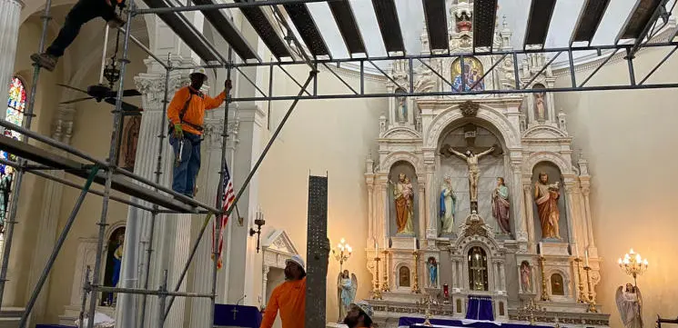 Artisans repainting saints within the All Saints Catholic Church sanctuary
